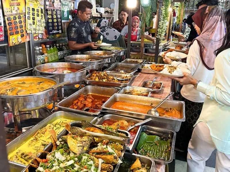 Sertai barisan untuk merebut pelbagai hidangan Melayu untuk makan tengahari anda di Rumah Makan Nasi Kampung